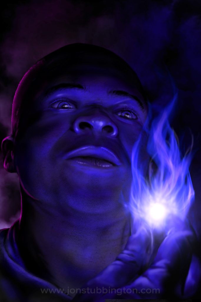 A close up view of a young man's face, illuminated by the blue flame he has conjured from his fingers.